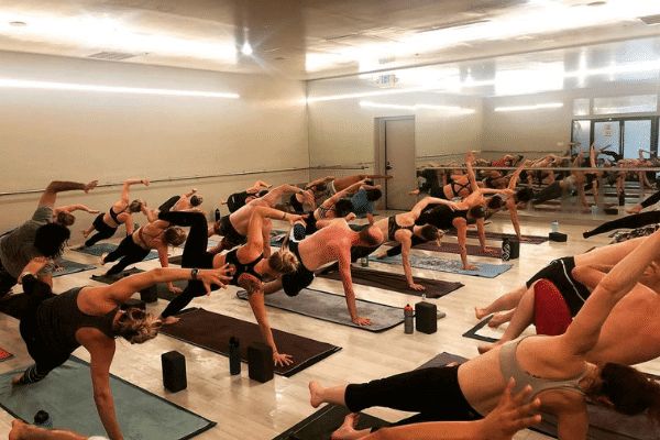 yoga students on yoga mats holding a yoga pose with arm raised