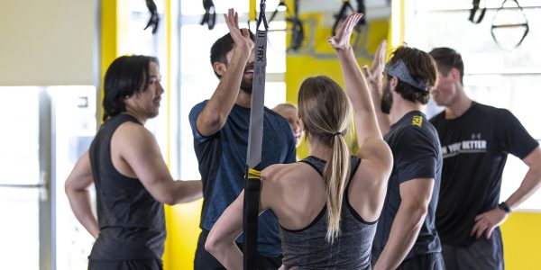 trx students high fiving each other next to workout equipment
